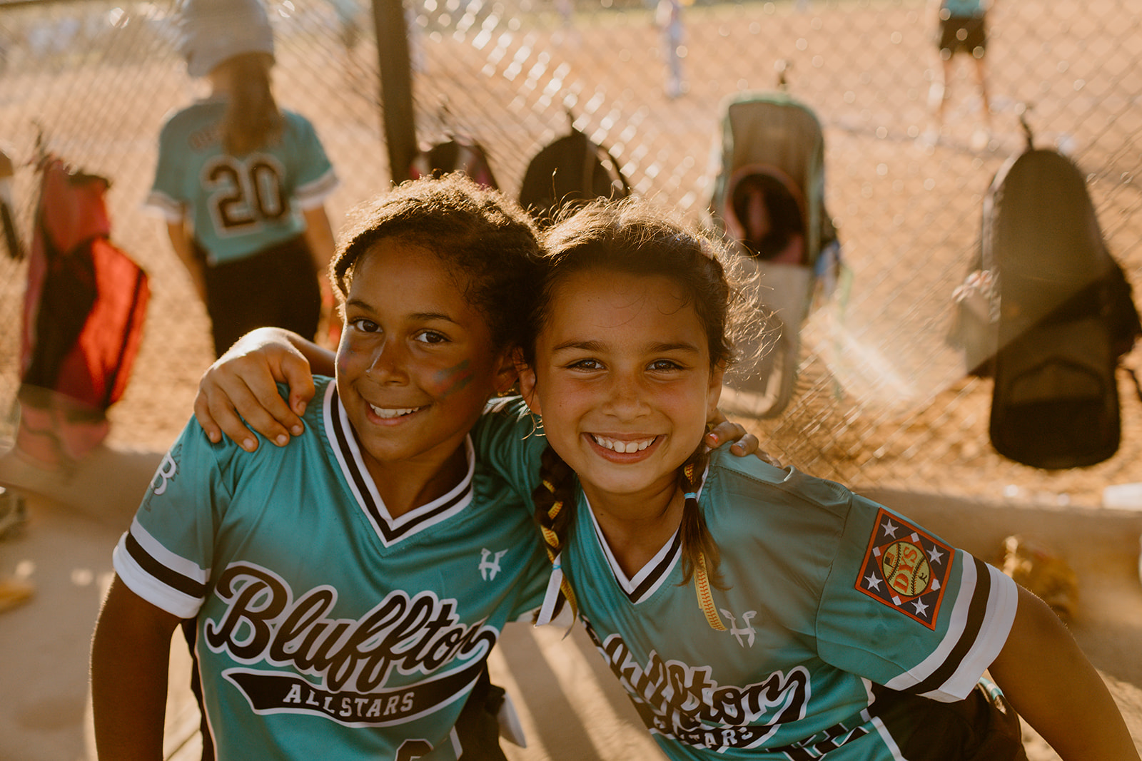 Two Bluffton All-Star teammates smiling together in the dugout