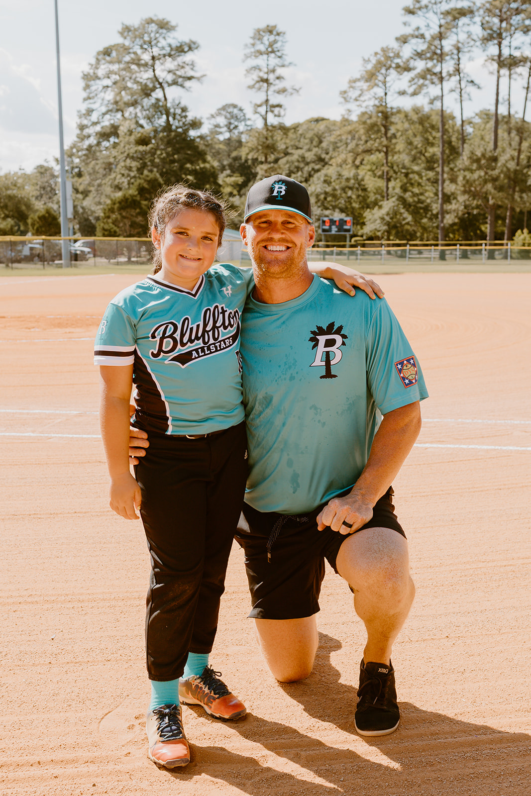 Bluffton All-Star player smiling with her coach on the infield