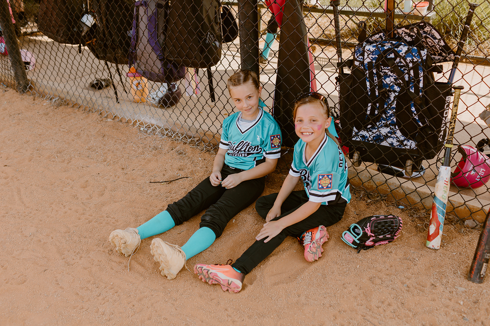 Two Bluffton All-Star players sitting together beside the dugout fence